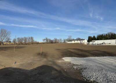 Site preparation and gravel application with farm home and outbuilding in background