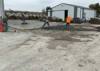Workers smooth concrete on a large concrete pad